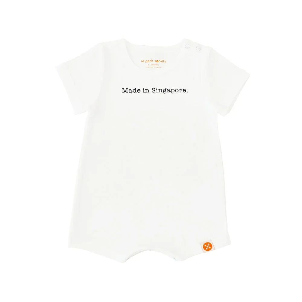 A simple white baby romper from Le Petit Society with a text at the front that says, "Made in Singapore."