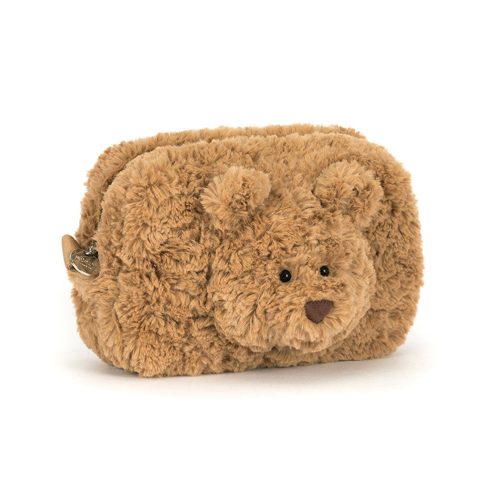 A plush, rectangular pouch in soft toffee-brown fur shaped like a teddy bear. Centered on the front is a round, stitched bear face with small ears, black eyes, and a tiny nose, all made of plush materials.