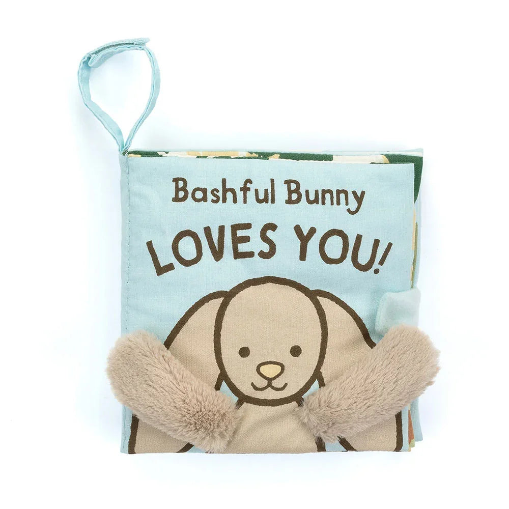 A soft fabric baby book with a bunny on the cover and fuzzy beige arms, titled "Bashful Bunny LOVES YOU!"