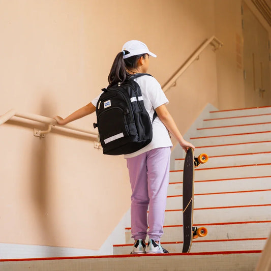 A primary school girl carrying the LPS kids double pocket school bag in cool black.