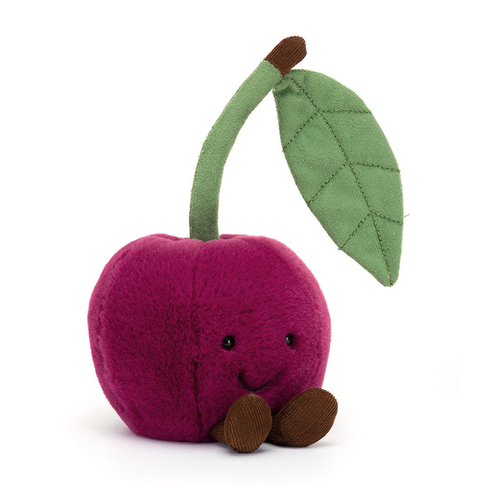 A front view of a cute, plush toy shaped like a cherry, with a smiling face and brown legs. The cherry features vibrant purple color, a green leaf, and a brown stem, giving it an endearing and playful design, perfect for babies or as a decorative piece.