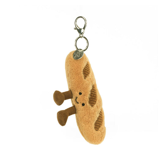 A hanging front view of a plush baguette keychain with embroidered smile, soft brown legs, and corduroy accents, complete with a silver clip for easy attachment.