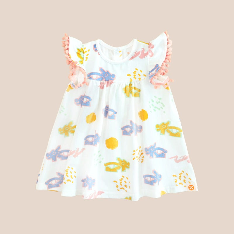 White baby girl’s flutter-sleeve dress with pink pompom trim and colorful dragon playground print in pastel blue, yellow, green, and pink.