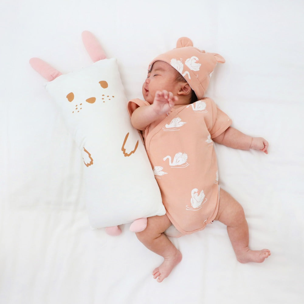 A peach-coloured baby kimono romper by Le Petit Society, featuring a print of swans.