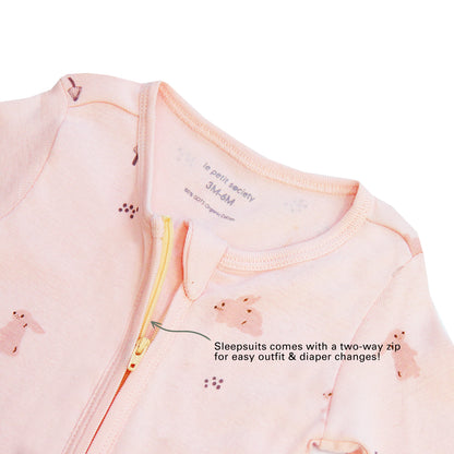An infographic demonstrating the two-way zipper of a pink baby zip sleepsuit, and its function of providing an easy access to outfit and diaper changes.
