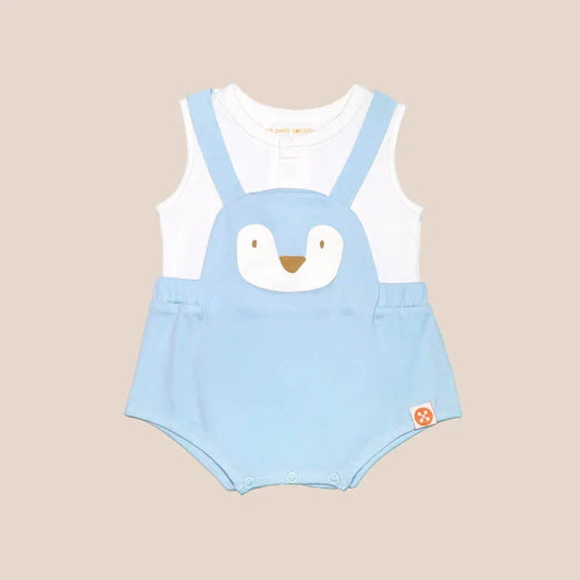 An animal-themed baby romper by Le Petit Society, featuring a blue penguin's face at the front, complete with blue bottoms and blue cross back straps over a white base.
