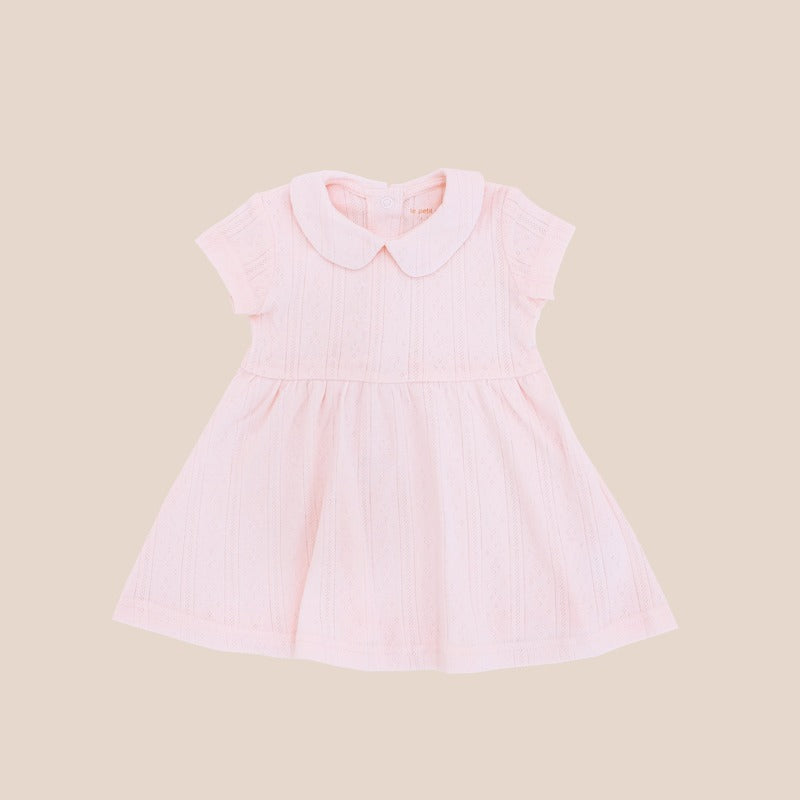 A baby girl dress from Le Petit Society. It comes with a peter pan collar and is made in a pink pointelle cotton.
