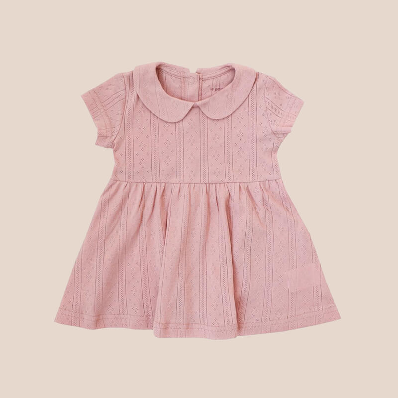 A baby girl dress from Le Petit Society. It comes with a peter pan collar and is made in a plum-coloured pointelle cotton.