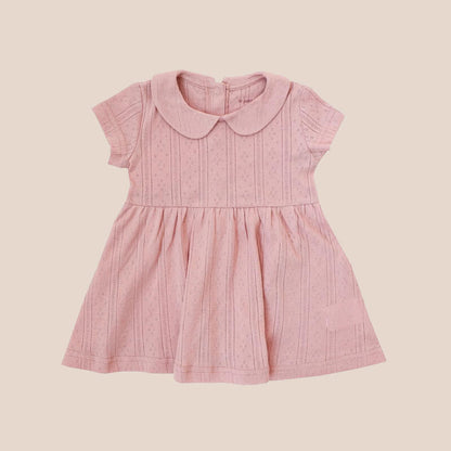A baby girl dress from Le Petit Society. It comes with a peter pan collar and is made in a plum-coloured pointelle cotton.