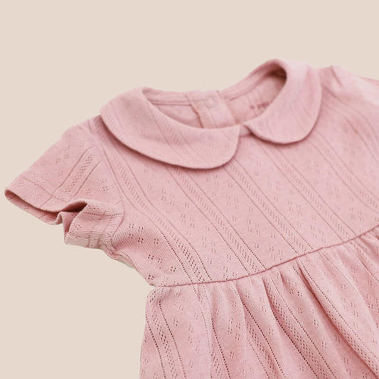 A baby girl dress from Le Petit Society. It comes with a peter pan collar and is made in a plum-coloured pointelle cotton.