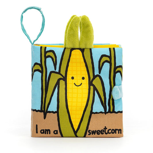 A soft fabric baby book showing a smiling corn on the cob against a blue sky background, titled "I am a sweetcorn".