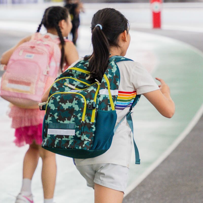 A primary school carrying the double pocket school bag in camouflage print.