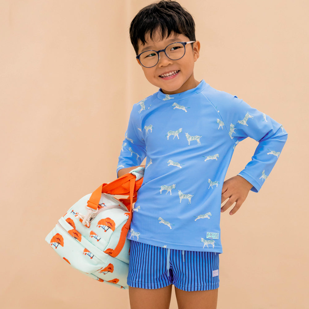 A primary school boy carrying the Le Petit Society's thermal lunch bag in croissant print.