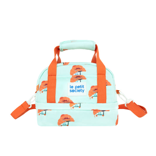 Le Petit Society's kid's thermal lunch bag in mint, with a croissant print and orange straps.