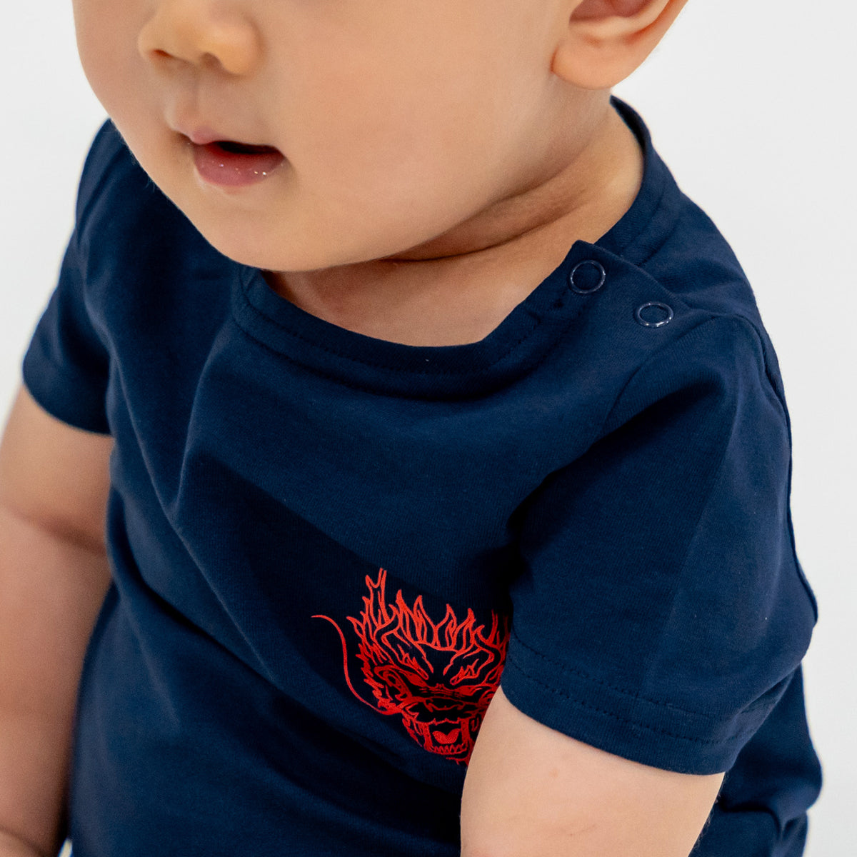 A close-up featuring the snap buttons of a baby romper in dragon print from Le Petit Society's Dragon Streetwear collection.