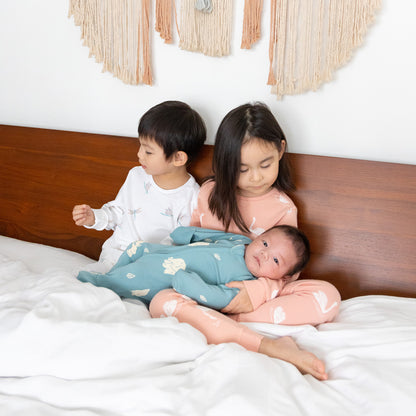 A baby, toddler and child all wearing sleepwear from Le Petit Society's organic line.
