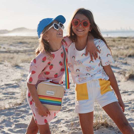 Two primary school girls with clothes and a rainbow thermal lunch bag from Le Petit Society.