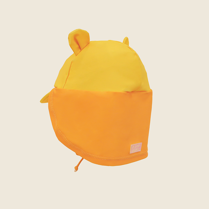 Baby Lion Sunhat side view showing lion ear details, orange neck flap and Le Petit Society logo patch in yellow and orange
