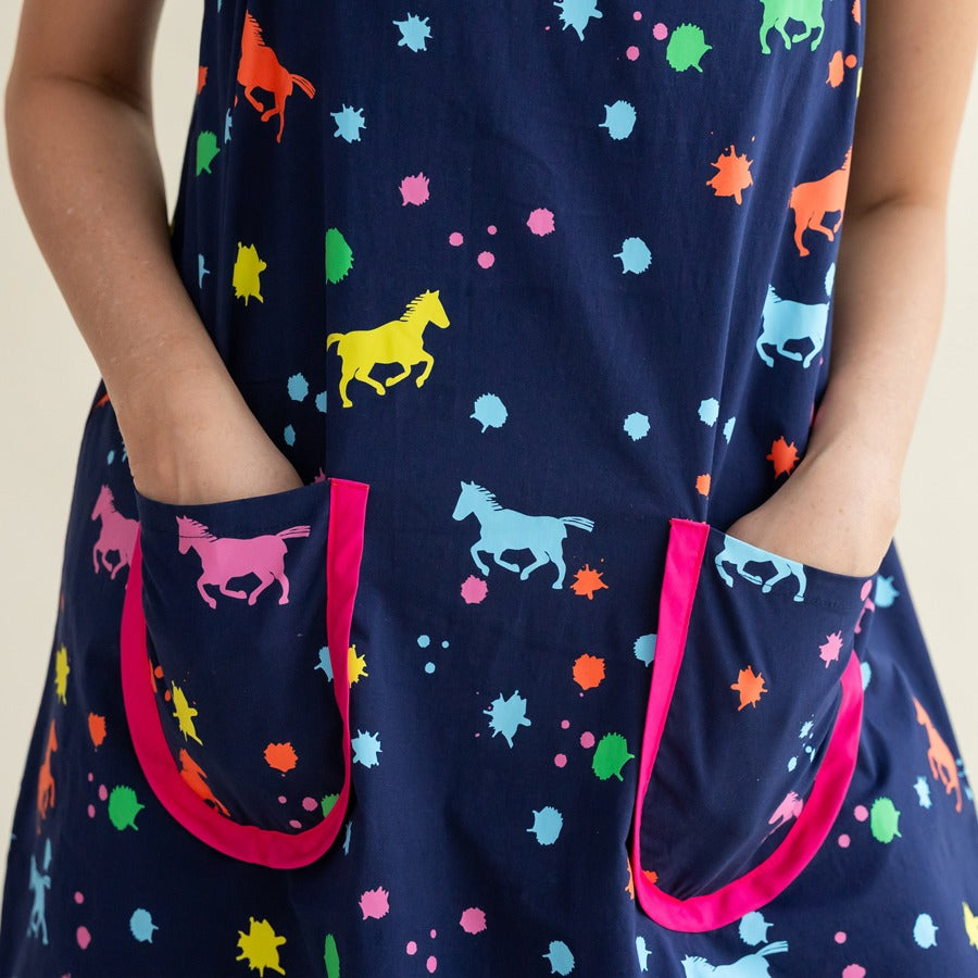 A close-up of the bright pink-trimmed pockets on the navy dress from the Le Petit Society x Sheila Sim CNY 2026 Rainbow Horse Collection, highlighting the colourful horse and paint-splatter print.