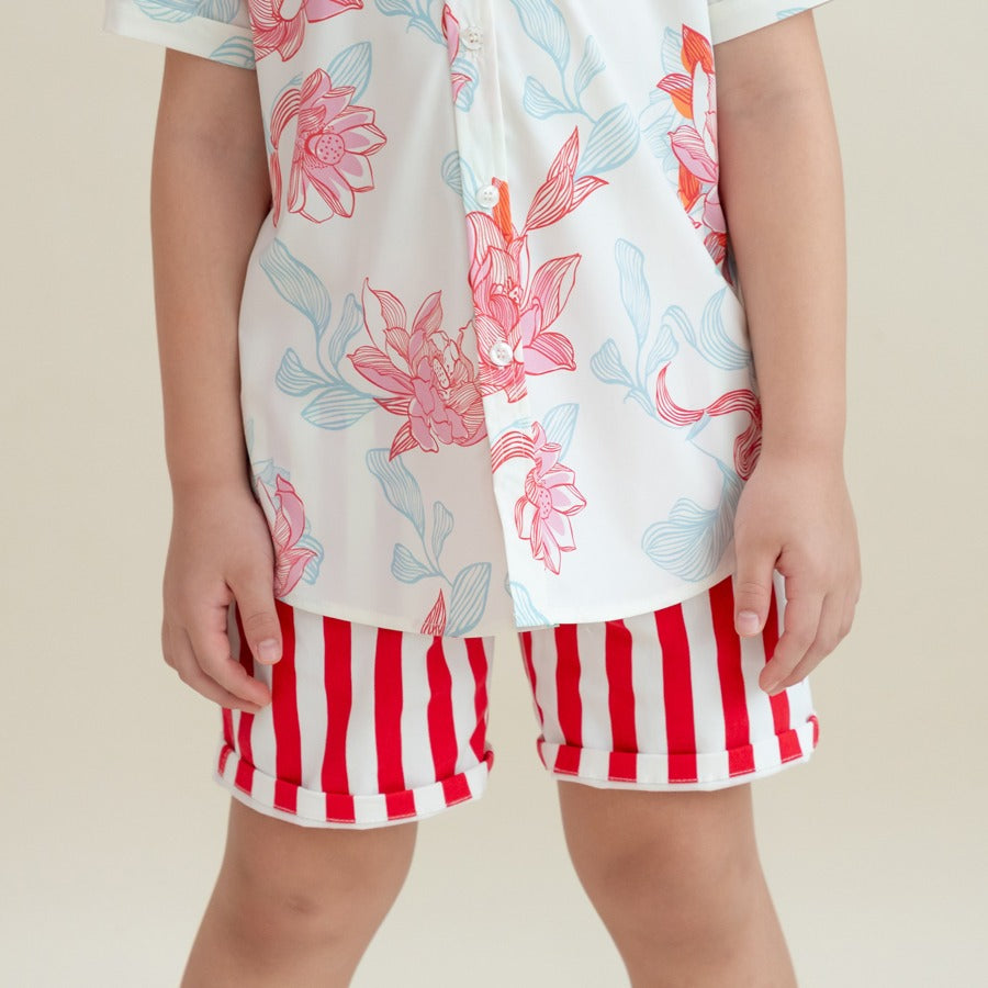 A child wearing red and white vertical striped shorts paired with a white shirt featuring pink and blue floral prints from the Le Petit Society x Sheila Sim CNY 2026 collection. The close-up shows the shorts’ rolled cuffs and the vibrant floral pattern on