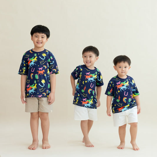 Three boys wear the Rainbow Horse tees from the Le Petit Society x Sheila Sim CNY 2026 Collection. The navy shirts are filled with bright, neon-coloured horse motifs, rainbows and lucky charms. Their playful poses and smiles bring out the fun, energetic s