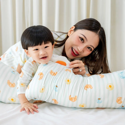 A mother and her baby boy wearing matching sleepwear and holding a pillow, all adorned with a playful breakfast food print from Le Petit Society.