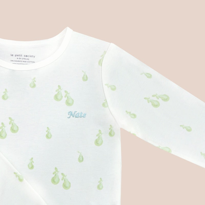 A close-up of a name embroidery personalisation on a kids pyjamas top from Le Petit Society, featuring a print of green pears.
