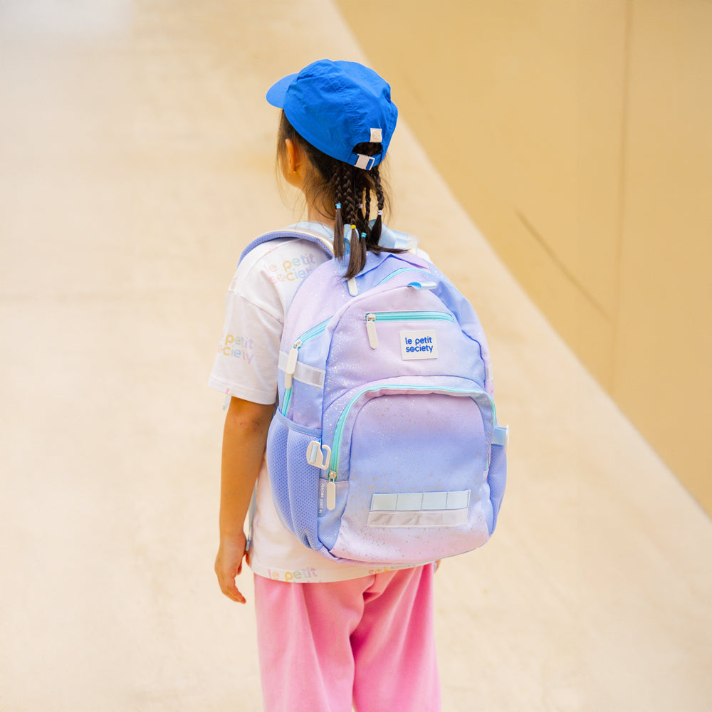 Primary school girl carrying the single pocket school bag in an ombre galaxy design.