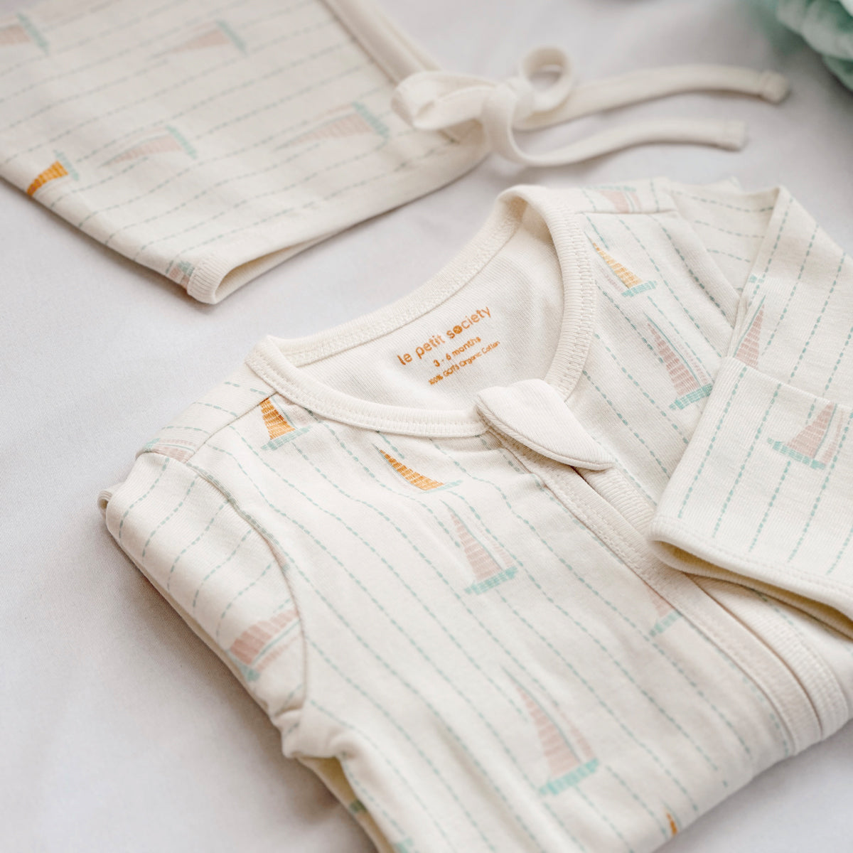 A close-up of an organic baby zip sleepsuit in sail boat print from Le Petit Society.