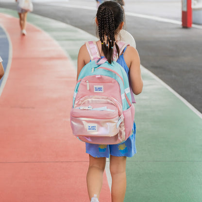 A primary school girl carrying the LPS kids single pocket school bag in an iridescent pink and gold design.