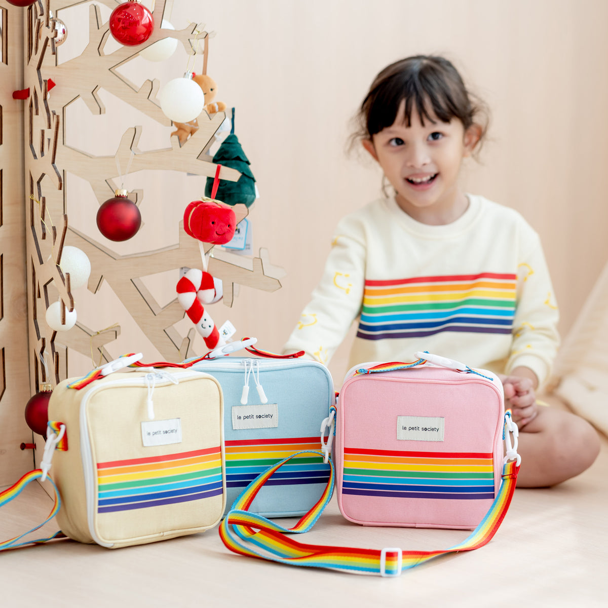 A little girl with thermal rainbow lunch bags from Le Petit Society.