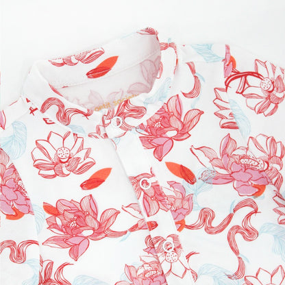 A close-up of the baby romper from the Le Petit Society x Sheila Sim CNY 2026 Lotus Collection. The soft mandarin collar and button placket frame the beautifully illustrated lotus blooms in coral and sky blue, giving the piece a gentle, festive elegance. 