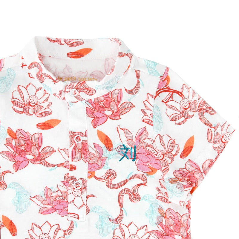 A detailed look at the baby romper from the Le Petit Society x Sheila Sim CNY 2026 Lotus Collection. The soft mandarin collar, gentle placket buttons, and vibrant lotus-print artwork come together in a clean, modern cheongsam style. A tiny embroidered cha