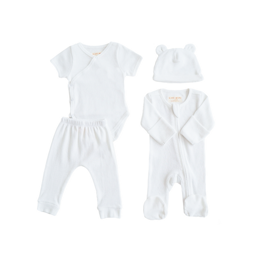 A baby organic essentials set in white by Le Petit Society, consisting of a zip sleepsuit, kimono romper, leggings and bear hat.