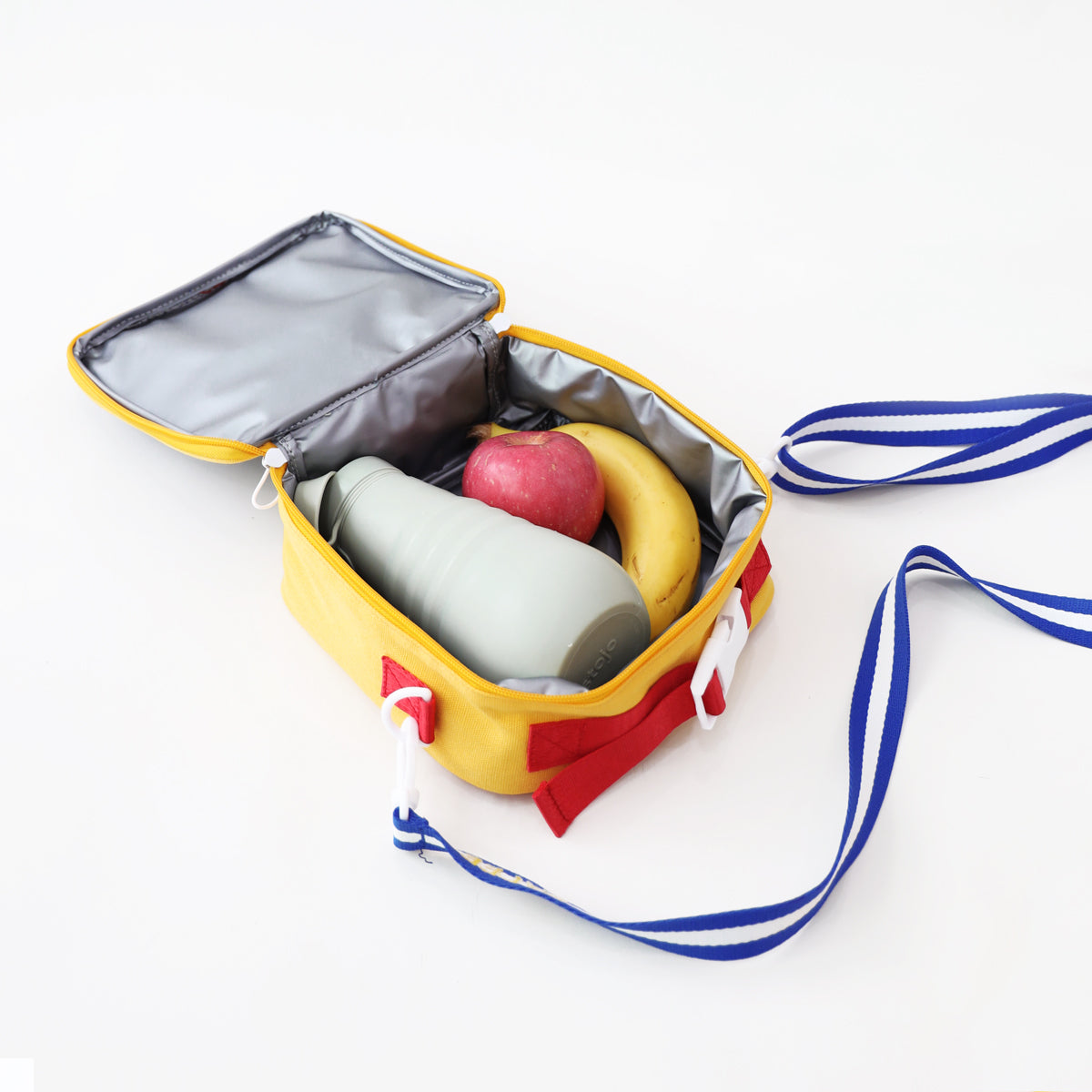Some fruits and a water bottle being stored in Le Petit Society's thermal lunch bag in colour block.