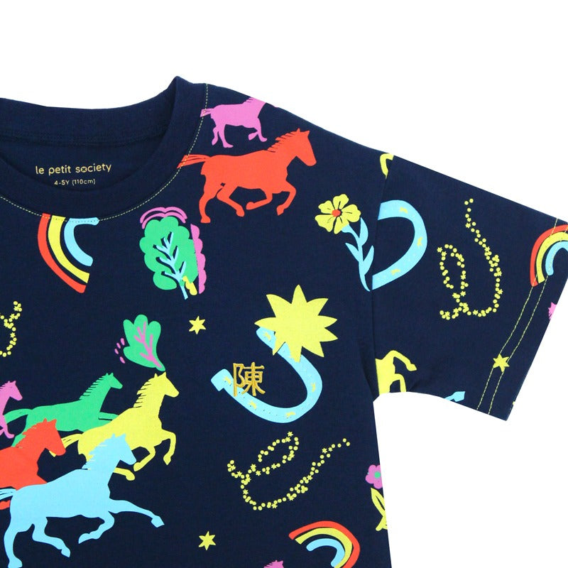 A detailed view of the Rainbow Horse tee from the Le Petit Society x Sheila Sim CNY 2026 Collection. The navy fabric is covered in bold neon illustrations of horses, lucky charms and rainbows, with a small gold personalised embroidery detail nestled besid