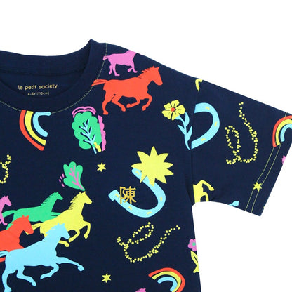 A detailed view of the Rainbow Horse tee from the Le Petit Society x Sheila Sim CNY 2026 Collection. The navy fabric is covered in bold neon illustrations of horses, lucky charms and rainbows, with a small gold personalised embroidery detail nestled besid