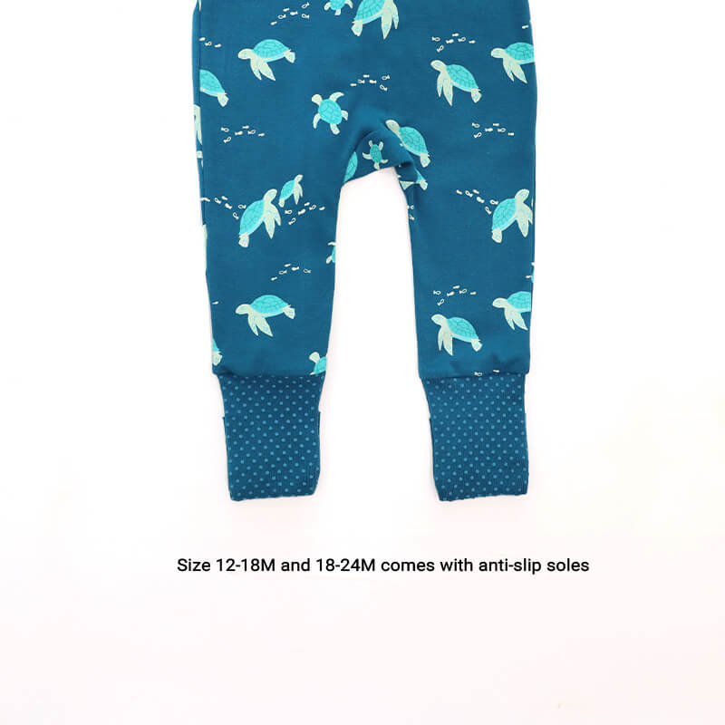 An infographic demonstrating the anti-slip soles of an organic zip sleepsuit in turtle print by Le Petit Society, which only come with sizes 12-18M and 18-24M. 