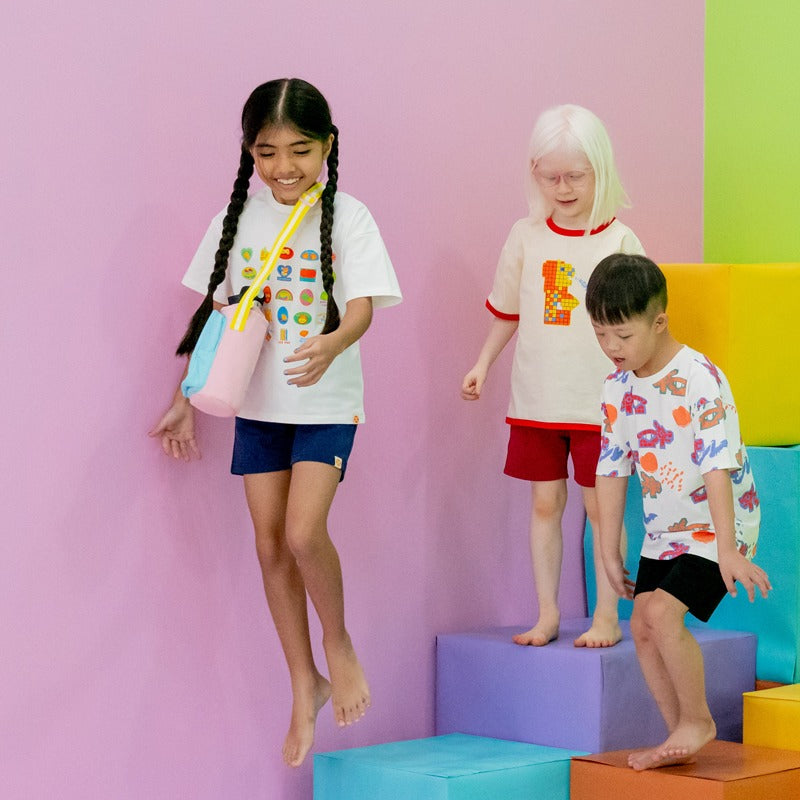 Three kids at play while wearing graphic tees from Le Petit Society.