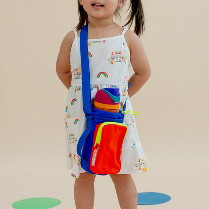 A little girl carrying a vibrant colourblock water bottle sling bag 