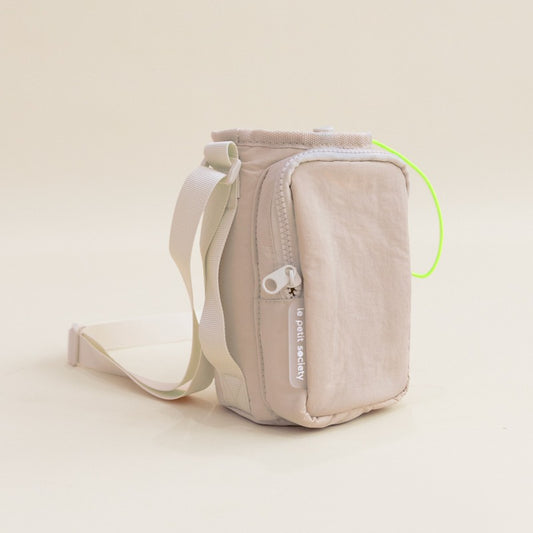 Beige water bottle sling bag with an adjustable strap and a front pocket.