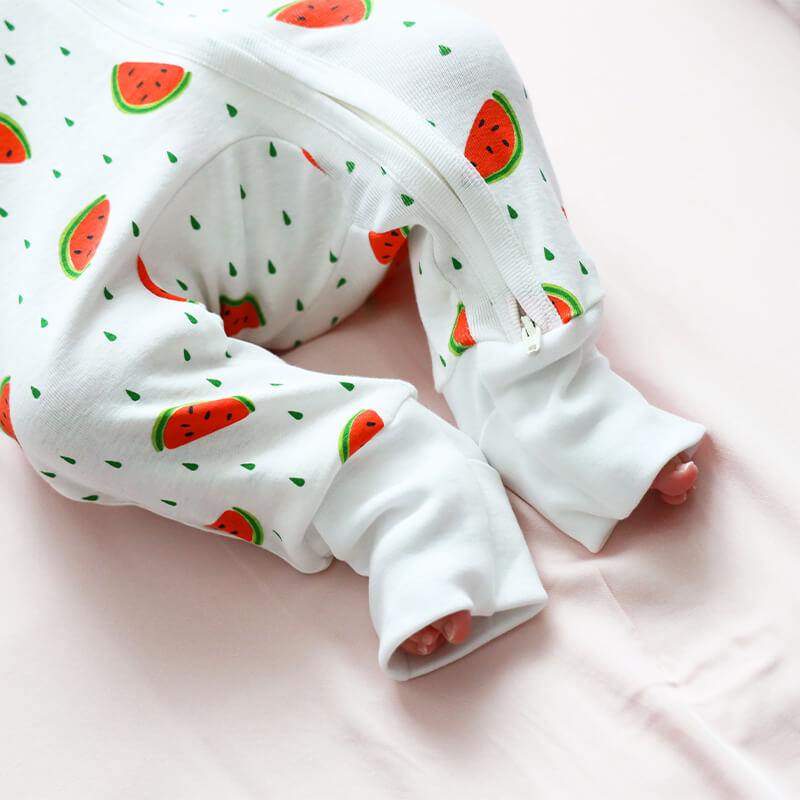 A baby wearing Le Petit Society's organic zip sleepsuit in watermelon print.
