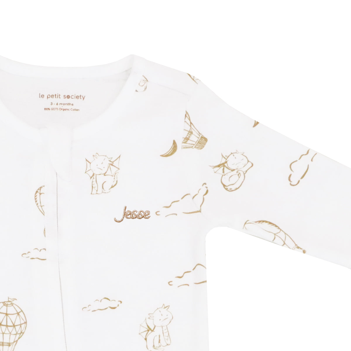 A close-up of a name embroidery personalisation on an organic zip sleepsuit in dragon print by Le Petit Society.